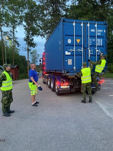 Personer öppnar en container som står lastad på en lastbil.